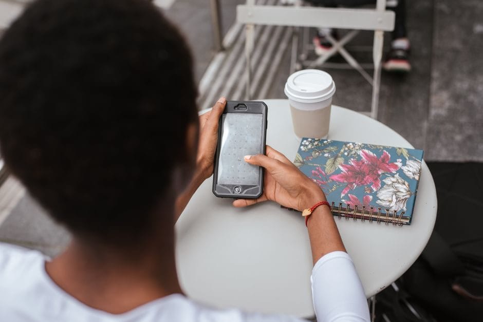 A woman checking messages on her phone at a cafe table in summer